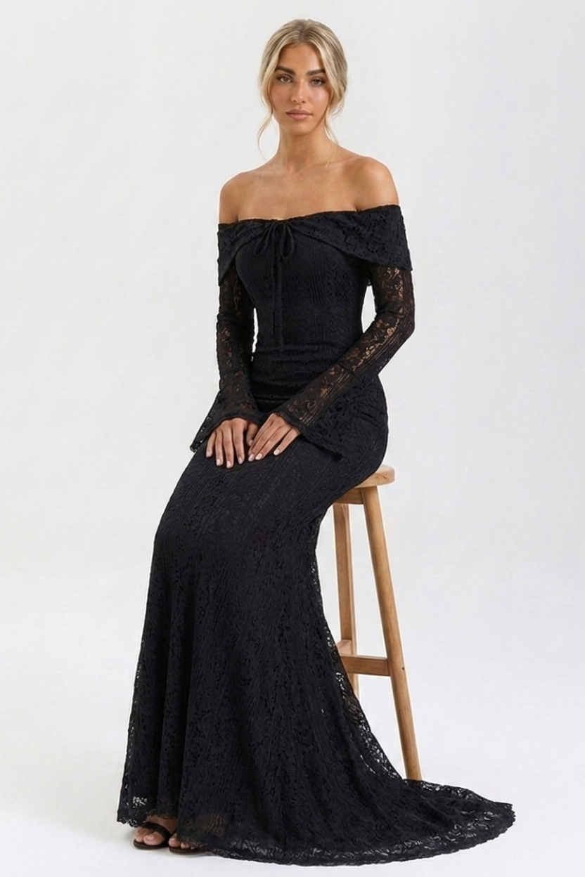 Woman wearing a black off-shoulder lace dress sitting on a wooden stool against a white background