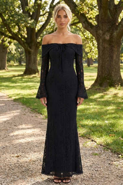 Woman in a black off-shoulder dress standing on a path in a park.